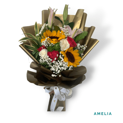 Amelia arrangement on a plain background: Cheerful sunflowers and roses wrapped in elegant gold and brown accents.