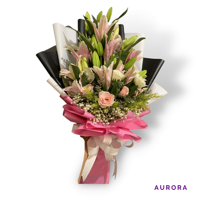 Aurora arrangement on a plain background: Elegant pink stargazer lilies and soft pink and white roses, wrapped in striking black, white, and pink accents.