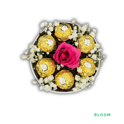 Bloom: A vivid pink rose surrounded by baby’s breath and six Ferrero Rocher chocolates, beautifully presented in white.