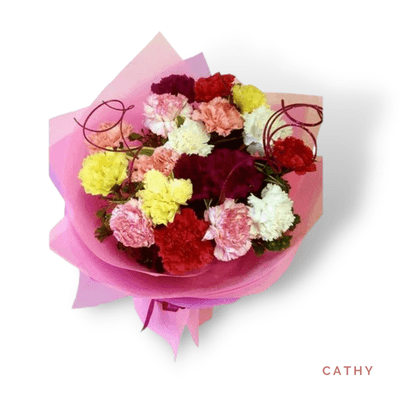 Cathy arrangement on a plain background: Colorful carnations in pink, red, white, yellow, and peach, wrapped in soft pink paper.