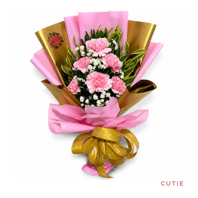 Cutie arrangement on a plain background: Fresh pink carnations with delicate fillers and greenery, wrapped in elegant pink and gold paper.