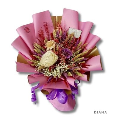 Diana: Elegant bouquet of cream and lavender wood roses with dried baby’s breath and colorful foliage, wrapped in pink and gold with a bold purple ribbon.