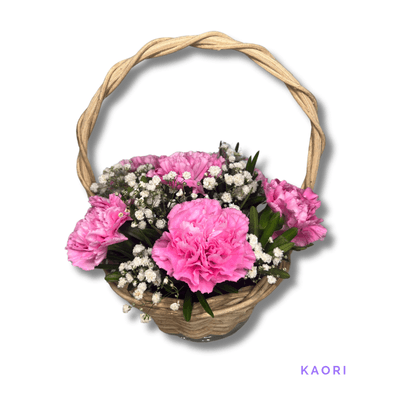 Kaori: Six delicate pink carnations with lush greenery, beautifully arranged in a wicker basket to express admiration and affection.